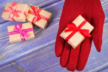 Hand of woman in red woolen gloves and wrapped gifts for Christmas, Valentine, birthday or other...