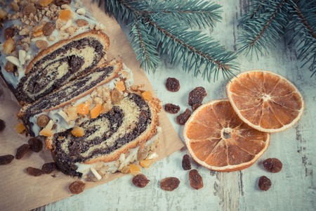 Vintage photo, Homemade poppy seeds cake and spruce branches on rustic board, dessert and decoration for Christmas, rolled up traditional polish poppy pieの写真素材