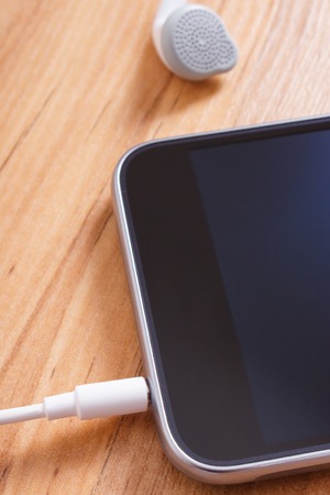 Mobile phone, smartphone with headphones on wooden boardの写真素材