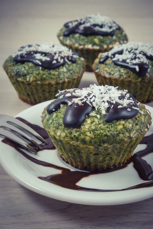 Vintage photo, Homemade fresh muffins baked with wholemeal flour with spinach, desiccated coconut and chocolate glaze, delicious, healthy dessert or snackの写真素材