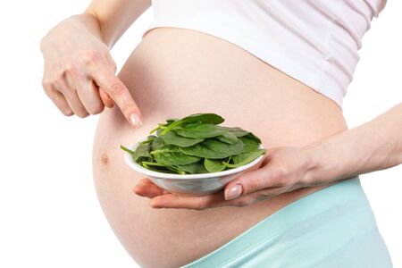 Pregnant woman showing portion of fresh green spinach, concept of healthy nutrition containing iron and vitamin during pregnancyの写真素材