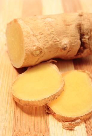 Slice and root of ginger on wooden background, concept of healthy nutritionの写真素材