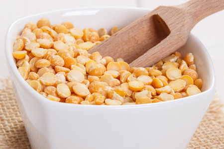 White bowl with split peas containing zinc and dietary fiber on white boards, natural sources of minerals, healthy lifestyle and nutritionの写真素材