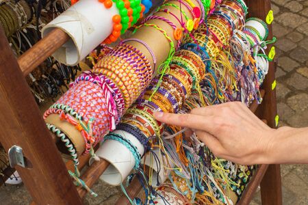 Hand of woman with colorful bracelets, shopping jewelry and womanly accessories on stall at the...