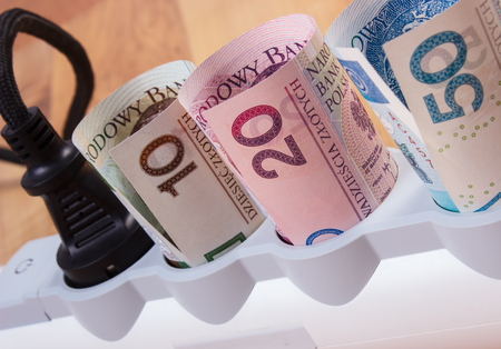 Rolls of polish currency money in electrical extension with connected plug, power board, concept of...