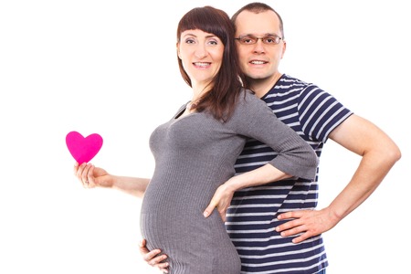 Happy smiling pregnant woman and her husband with heart of paper, concept of extending family and expecting for newbornの写真素材