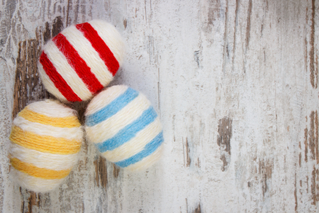 Easter eggs wrapped woolen string on old rustic wooden background, copy space for inscription or textの写真素材