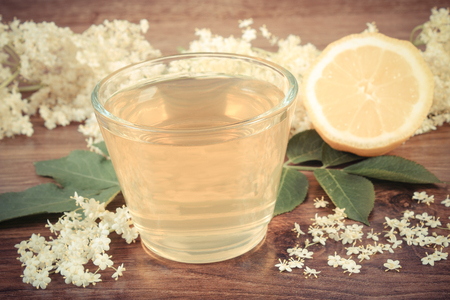 Vintage photo, Glass of refreshment healthy juice, elderberry flowers and lemon on rustic board, alternative medicine and therapyの写真素材