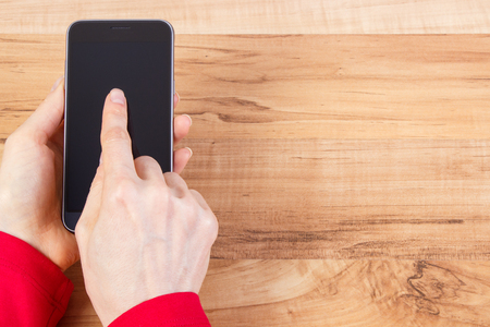 Hand of woman holding smart phone and touching blank screen, using mobile telephone, copy space for textの写真素材