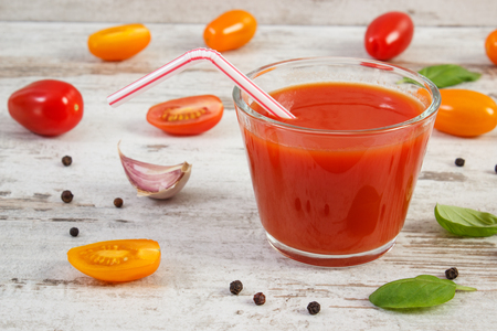 Glass of fresh tomato juice and vegetables with spices on old rustic wooden background, concept of healthy nutritionの写真素材