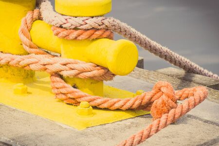 Vintage photo, Rope and yellow mooring bollard in port, closeup and detail of seaportの写真素材