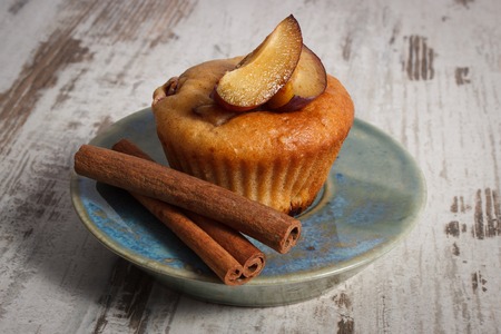 Homemade fresh baked muffins with plums and cinnamon sticks on plate, delicious dessertの写真素材