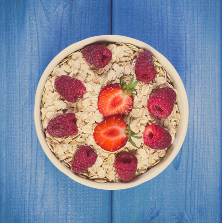 Vintage photo, Fresh prepared oat flakes or oatmeal with strawberries and raspberries in glass bowl, concept of diet, healthy lifestyles and nutritionの写真素材