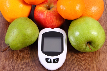 Glucose meter for checking and measuring sugar level and fresh ripe fruits, concept of diabetes, healthy lifestyles and nutritionの写真素材