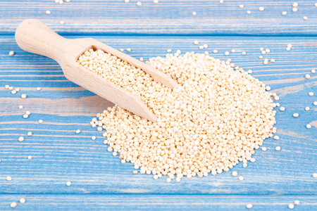 Heap of quinoa seeds with wooden scoop as source vitamins, healthy nutrition conceptの写真素材