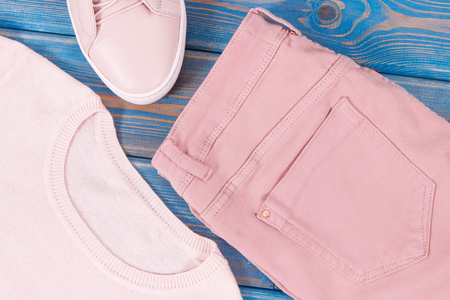Womanly pink leather shoes, sweater and pants lying on old blue boardsの写真素材