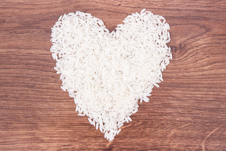 Heap of white rice in shape of heart on rustic board, concept of healthy nutritionの写真素材