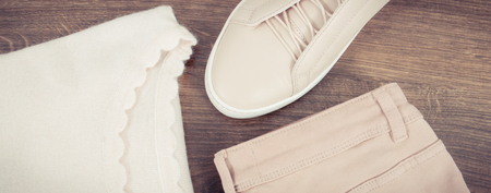 Vintage photo, Womanly pink leather shoes, pants and clothing lying on old rustic boardsの写真素材