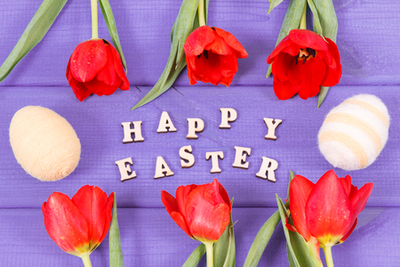 Inscription Happy Easter, fresh red tulips and eggs wrapped woolen string on boards, festive decoration conceptの写真素材