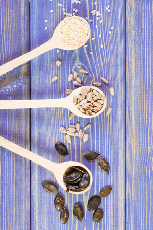 Sunflower, pumpkin and sesame seeds with wooden spoon on boards, concept of healthy nutritionの写真素材
