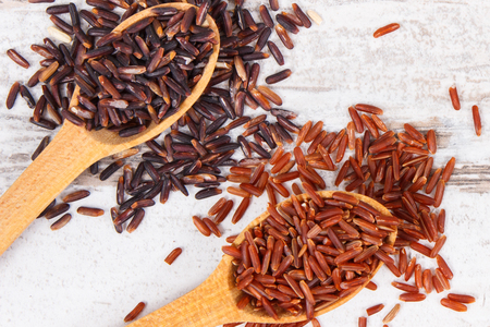 Black and red rice on wooden spoons on rustic board, concept of healthy, gluten free nutritionの写真素材