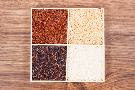 White, brown, black and red rice on rustic board, concept of healthy, gluten free nutritionの写真素材