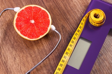 Digital electronic bathroom scale for weight of human body, tape measure and medical stethoscope with fresh grapefruit, concept of healthcare, healthy lifestyles and slimmingの写真素材