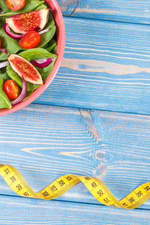 Fruit and vegetable salad in bowl and tape measure, concept of diet, slimming, healthy lifestyles and nutritionの写真素材