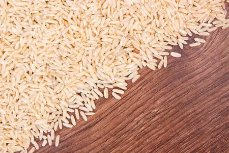 Heap of brown rice, concept of healthy nutrition, copy space for text or inscription on rustic boardの写真素材