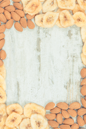 Frame of almonds and banana chips as source carbohydrates, dietary fiber, vitamins and minerals, concept of healthy and nutritious eatingの写真素材