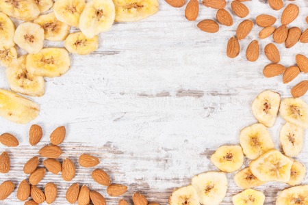 Frame of almonds and banana chips as source carbohydrates, dietary fiber, vitamins and minerals, concept of healthy and nutritious eatingの写真素材