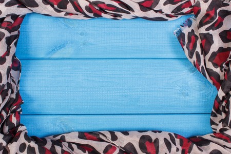 Frame of colorful shawl for woman on blue boards, womanly warm clothing for autumn or winter, copy...