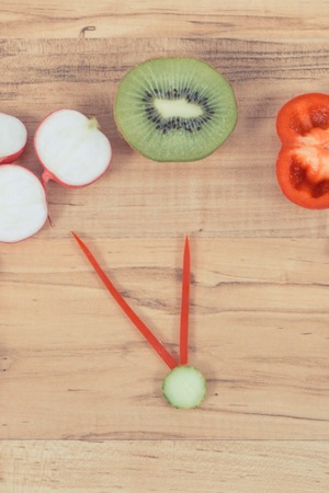 Clock made of fresh ripe fruits and vegetables showing time for healthy eatingの写真素材