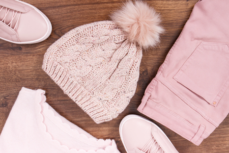 Pink leather shoes, pants, woolen cap and sweater for woman lying on rustic boardの写真素材