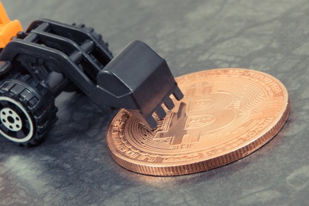 Bitcoin as virtual money and miniature excavator, concept of mining cryptocurrency and international network paymentの写真素材