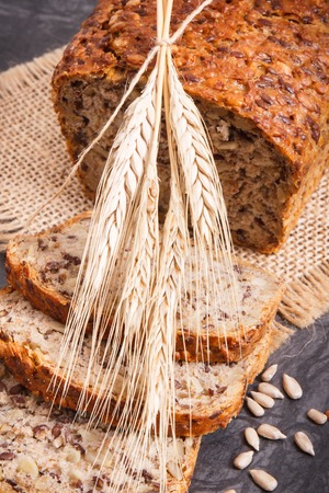 Fresh baked wholegrain bread with ingredients for baking and ears of rye or wheat grainの写真素材