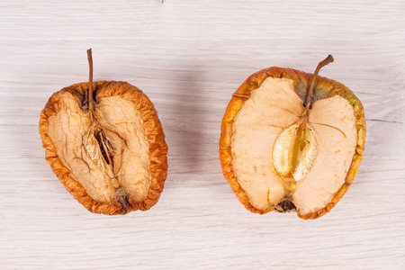 Old wrinkled moldy apple on board, unhealthy and disgusting eating