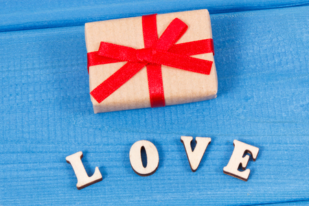 Wrapped gift with ribbon and word love as surprise for Valentines Day, birthday or other celebrationの写真素材