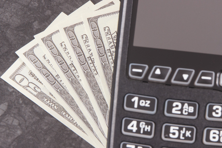 Payment terminal and currencies dollar. Finance concept and choice between cashless or cash paying in different placesの写真素材