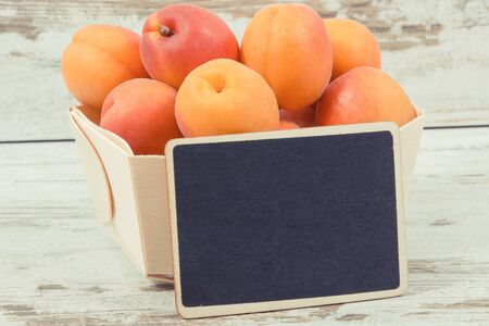 Fresh apricot in wooden box as healthy snack or dessert containing natural vitamins. Copy space for text or inscription on black boardの写真素材