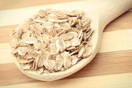 Rye flakes with wooden spoon. Healthy ingredients as source dietary fiber and natural minerals