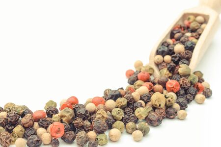 Colored pepper with wooden scoop or spoon on white background. Healthy cooking spice concept. Place for textの写真素材