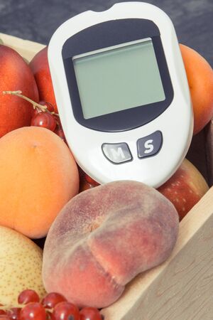Glucometer for checking sugar level and fresh ripe fruits. Healthy food during diabetes containing natural minerals and vitaminsの写真素材