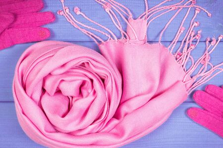 Woolen pink gloves and shawl for woman on boards. Warm clothing for autumn or winterの写真素材