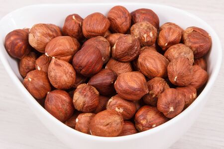 Hazelnuts in white bowl as source healthy natural vitamins and minerals, nutritious eating concept