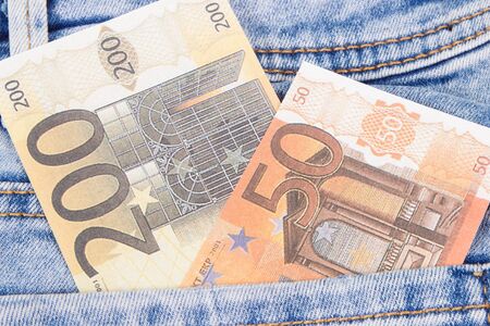 Currencies euro in blue jeans pocket. Concept of cash paying for shoppingの写真素材