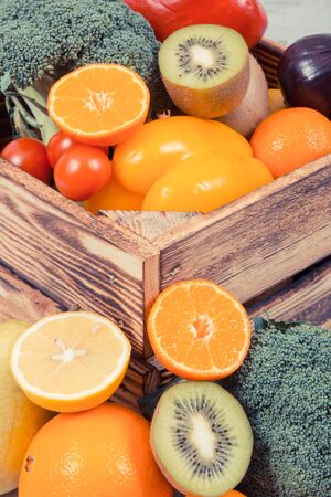 Heap of fresh ripe fruits with vegetables in rustic wooden box. Nutritious food containing healthy minerals and vitaminsの写真素材