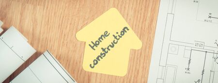 Diagrams or electrical construction drawings and yellow paper in shape of house with text home construction, concept of building homeの写真素材