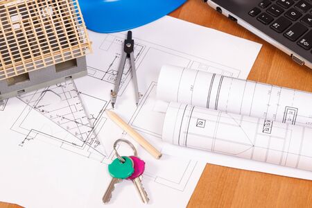 Home keys, electrical diagrams or drawings and accessories for use in engineer jobs lying on desk in...