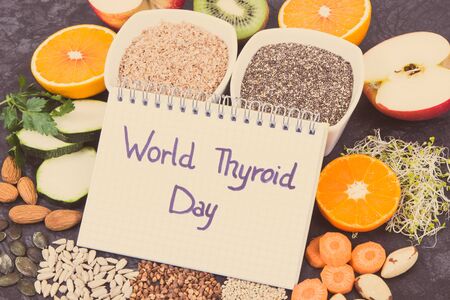 Nutritious ingredients and inscription World Thyroid Day written in notepad. Healthy food containing...